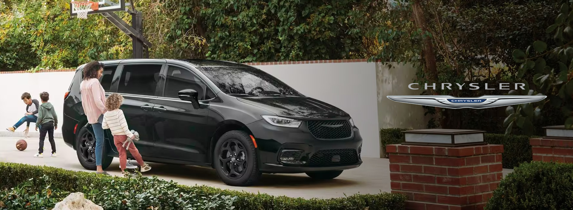 Black Chrysler Pacifica minivan parked in a residential driveway,